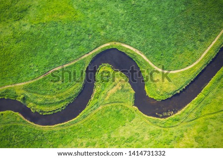 Top view drone shot of a green field and river 