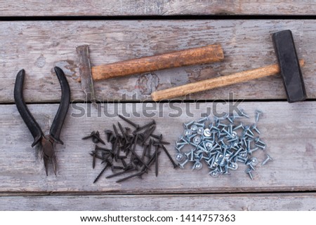 Construction tools on wooden background. Two old hammers, pliers and many screws on rustic wooden boards. Repair concept.
