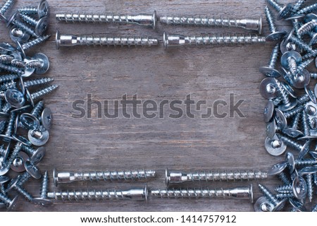 Frame from screw nails on wooden background. A lot of silver screws and copy space. Repair concept.