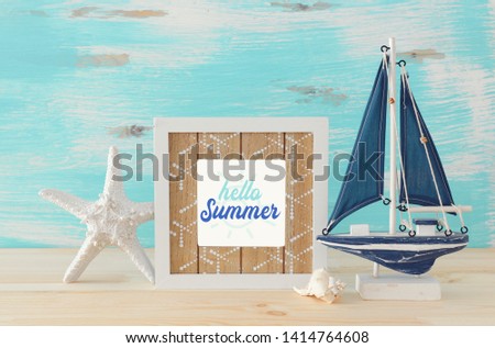 Nautical concept with photo frame and sail boat over wooden table