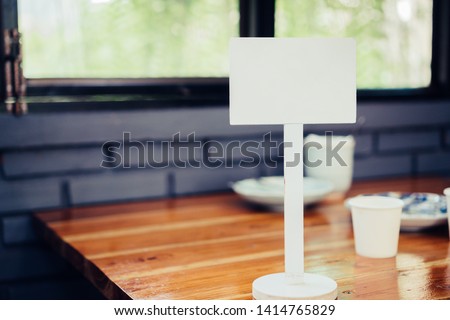 Mock up white Label for blank menu frame in restaurant cafe. Stand booklet sheets paper tent card on table cafeteria display your product blurred background insert  text of customer. Space for texting
