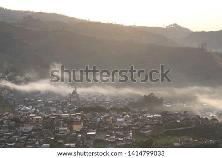 morning fog enveloped a village taken from the highlands
