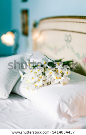 Spring white iris flowers on clean white bedding with vintage mirror at home. Romantic mood of the morning. Good morning concept.