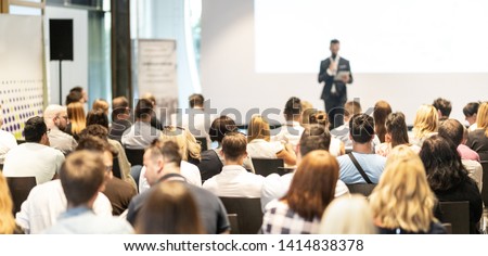Male speaker giving a talk in conference hall at business event. Audience at the conference hall. Business and Entrepreneurship concept. Focus on unrecognizable people in audience. Royalty-Free Stock Photo #1414838378