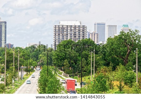 Divided highway with lots of lush foliage and green stoplight with cars and trucks and pedestrians leading to downtown Tulsa Oklahoma USA