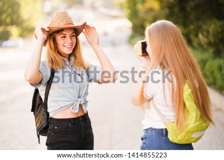 tourism, vacation, photograph, sightseeing. Young student taking pictures of her friend in the city