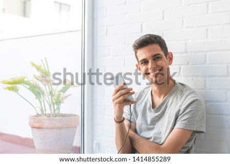 young man or teenager with mobile phone at home