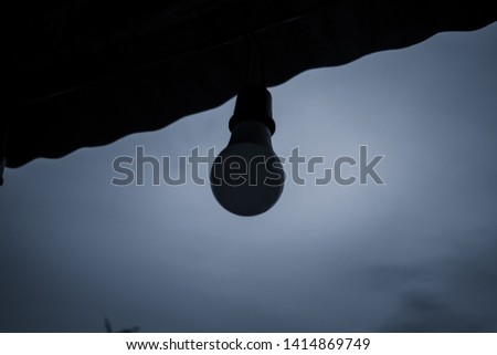 Old light bulbs hanging under the eaves against the background of the evening sky