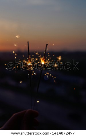 holding sparklers firework (Bengal fire) bokeh with blur sky morning background, blue dark tone, silhouette, out of focus