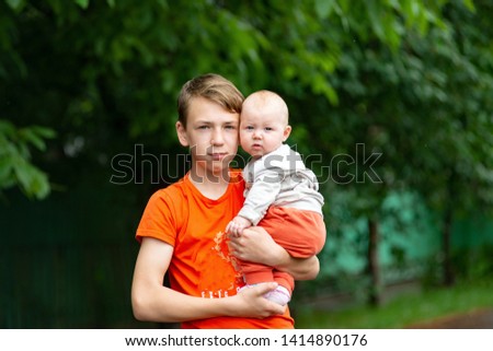 Handsome and adult boy holding a small child in his arms, portrait of a young happy family.