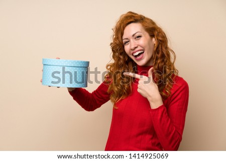 Redhead woman with turtleneck sweater holding gift box