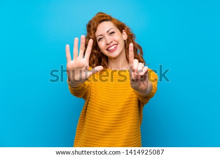 Redhead woman with yellow sweater counting six with fingers Royalty-Free Stock Photo #1414925087