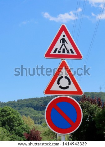 Traffic signs: triangle warnings of pedestrian crossing and roundabout movement ahead, round prohibitory no parking