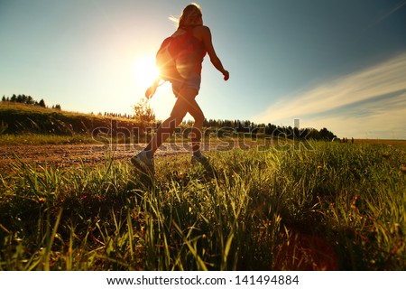 Hiker with backpack walking on a gravel road Royalty-Free Stock Photo #141494884