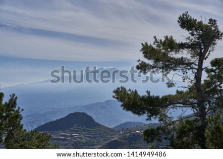 Landscape Picture on the active volcano mount Etna in sicily, Italy at backgound, in front is typical italian or sicilian highland countryside in green. Picture is taken in early spring cloudy day.
