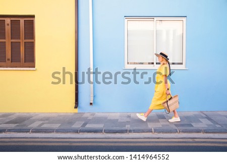 Beautiful blonde woman walking in yellow dress at Paphos old city with colorful door and house. Travel to Cyprus Royalty-Free Stock Photo #1414964552