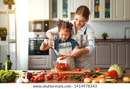 happy family mother with child girl   preparing vegetable salad at home
