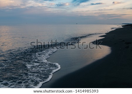 Black magnetic sand beach of Black sea in Ureki, Georgia.Sunset in a cloudy sky on the sea.Rest on black sea.trip to the sea of Georgia
