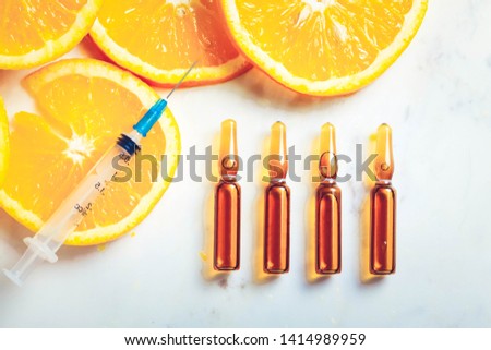 Vitamin C, natural anti aging cosmetics serum ampullas and syringe, toned Royalty-Free Stock Photo #1414989959