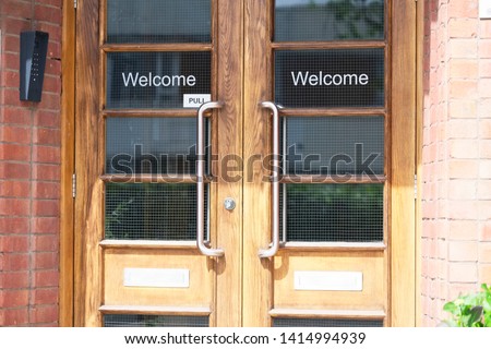 Welcome greeting entrance sign on double wooden glazed doors at office work place