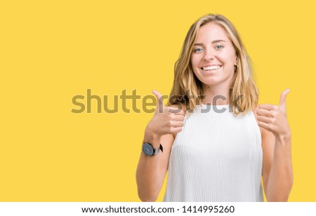 Beautiful young elegant woman over isolated background success sign doing positive gesture with hand, thumbs up smiling and happy. Looking at the camera with cheerful expression, winner gesture.
