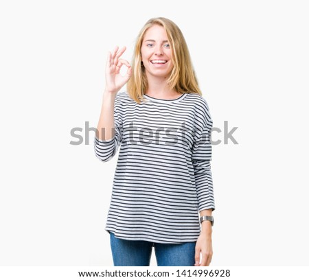 Beautiful young woman wearing stripes sweater over isolated background smiling positive doing ok sign with hand and fingers. Successful expression.