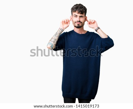 Young handsome man over isolated background Smiling pulling ears with fingers, funny gesture. Audition problem