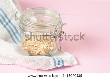 Cute and small glass pot with oat on pink background