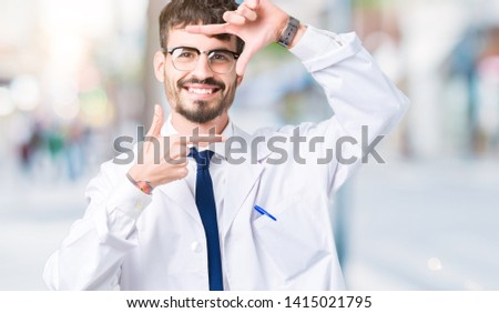 Young professional scientist man wearing white coat over isolated background smiling making frame with hands and fingers with happy face. Creativity and photography concept.