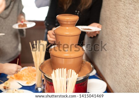 Vibrant Picture of Chocolate Fountain Fontain on a children kids birthday party with a kids playing around and dipping marshmallows and fruits into the fountain