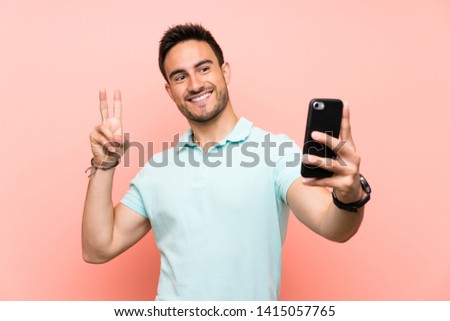 Handsome young man over isolated background making a selfie