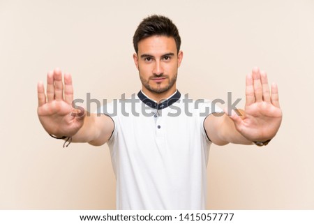 Handsome young man over isolated background making stop gesture and disappointed