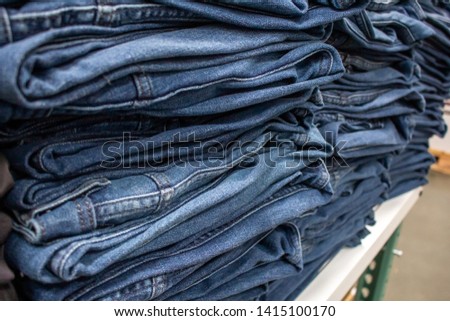 A view of several folded pairs of jeans or denim pants on a table at a department store.