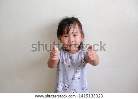 Asian child girl is raising two thumbs up. Isolated on white background.