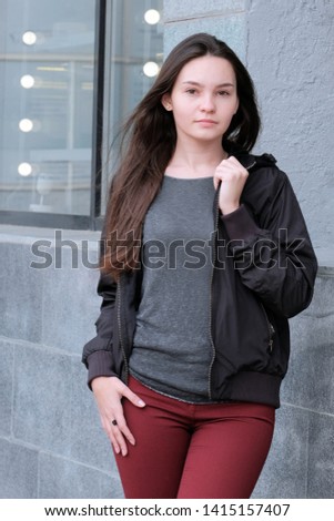 Outdoor walks in spring, summer and autumn. Beautiful serious girl looking at the camera. Portrait of a young woman on the street.