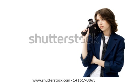 Beautiful brunette girl in a jacket and jeans posing on a white background with an old vintage movie camera, in isolation