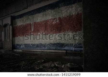 painted flag of costa rica on the dirty old wall in an abandoned ruined house. concept