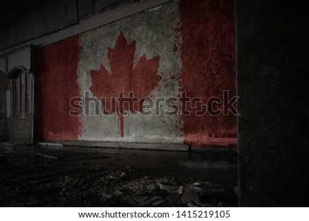 painted flag of canada on the dirty old wall in an abandoned ruined house. concept