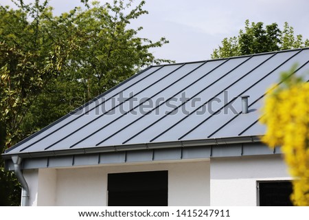 Metal standing seam roof on a residential home Royalty-Free Stock Photo #1415247911