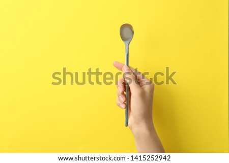 Woman holding empty soda spoon on color background, closeup. Space for text