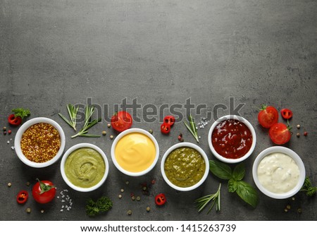 Bowls with different sauces and ingredients on gray background, flat lay. Space for text Royalty-Free Stock Photo #1415263739