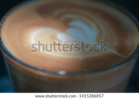 Close up or macro photo of a cup cappuccino coffee art floating on top. Royalty high-quality free stock photo image a cup of cappuccino coffee foam art with romantic heart shape from milk surface
