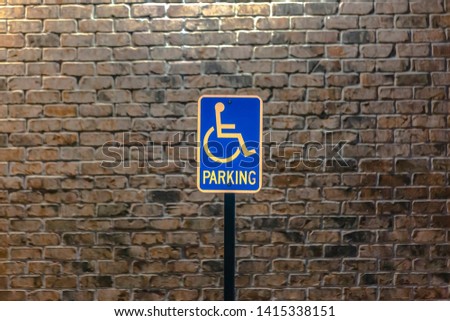 Handicap parking sign against a stone brick wall illuminated by sunlight