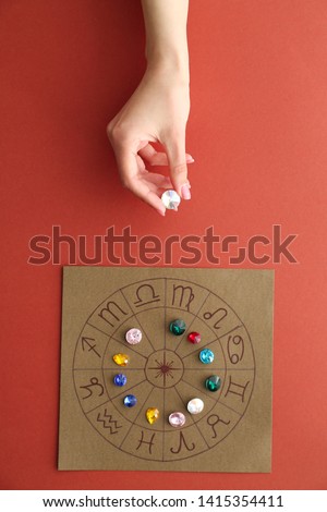Astrological horoscope with birthstones and female hand on color background Royalty-Free Stock Photo #1415354411