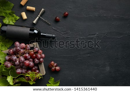 Top view of tasty fruit plate with the wine bottle on the black stone on a kitchen plate on the black stone background, top view, copy space. Gourmet food and drink.