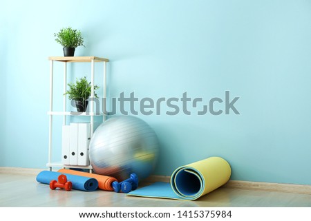 Set of sports equipment with fitness ball near wall