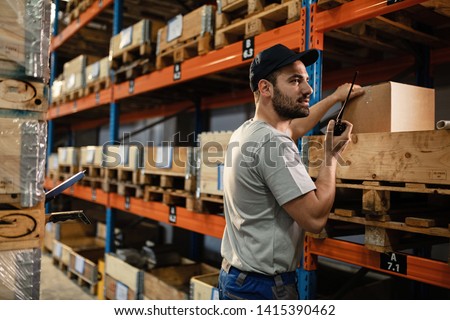 Warehouse worker talking over walkie-talkie while organizing package shipment for distribution.  Royalty-Free Stock Photo #1415390462