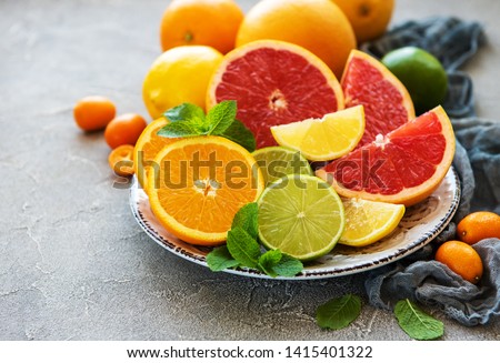Plate with citrus fresh fruits on a concrete background Royalty-Free Stock Photo #1415401322