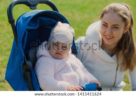 Young mother with a baby in a stroller in a summer park.