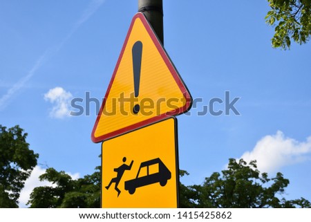 Yellow weird road warning sign. Car hits man (unusual fun concept). Closeup.